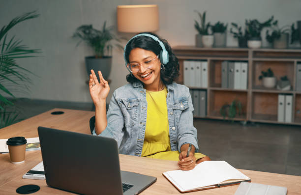 istock Student, laptop and waving for video call in night studying, distance learning or education for college, university or school. Smile, woman and greeting elearning webinar or asking questions at home 1496869762