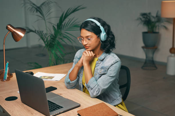 istock Student, laptop or video call for night studying, distance learning and education for college, university or school. Serious, woman or listening to elearning webinar in home living room for degree 1496869764