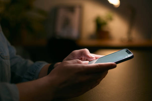 istock Close Up Of Woman Using Mobile Phone At Home At Night With Illuminated Screen 1496870039