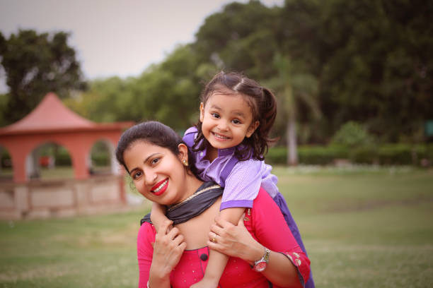 Cheerful Candid image of small schoolgirl and her mother outdoors in the public park.