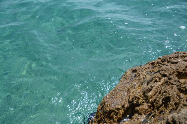 istock Background shot of turquoise sea water surface next to rock. 1496872402