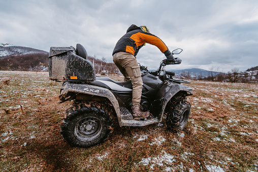 A man drives an ATV in the mud. Drift driving an ATV quad in mud and snow.