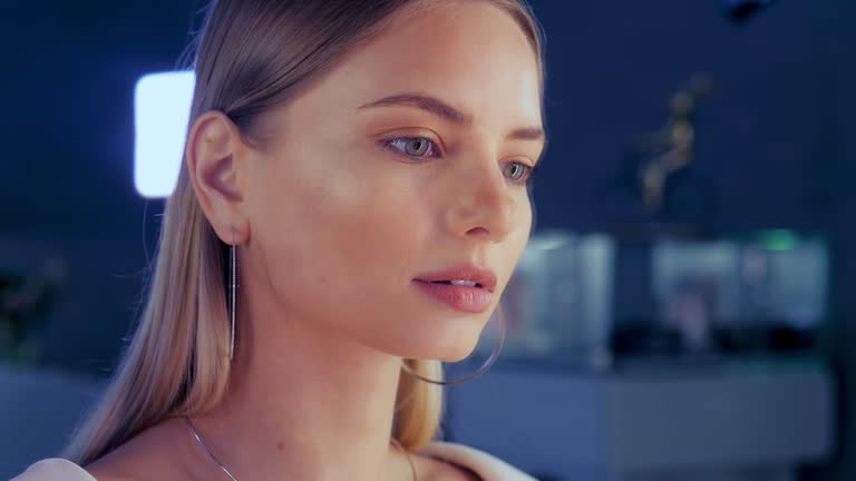 Magic beautiful model stands in mirror in a jewelry store tries on a gold diamond necklace that sparkles on the girl. Girl is adorned with golden jewelry and diamonds in a luxurious boutique.