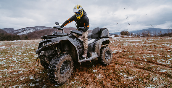 A man drives an ATV in the mud. Drift driving an ATV quad in mud and snow.