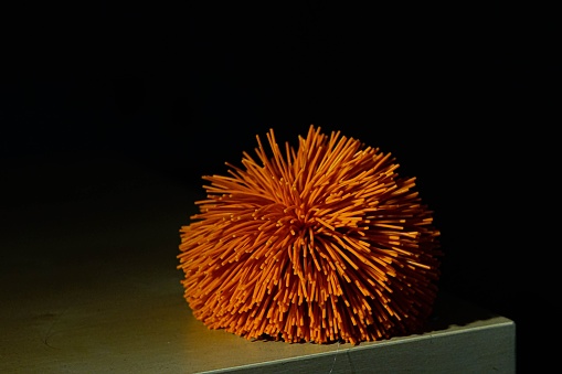 A small orange stress relief toy laying on a tabletop
