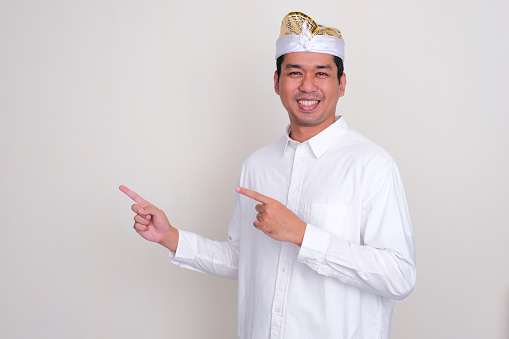 Balinese man smiling and pointing both hands to the right side