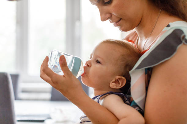 istock Thirsty Baby Boy Drinks Water From The Baby Bottle 1496877628