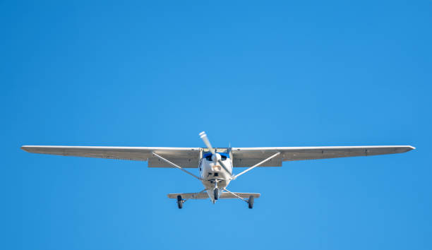 istock Small white plane with blue stripes of a cessna propeller flying in a clear sky before landing on Sabadell Airport 1496878276