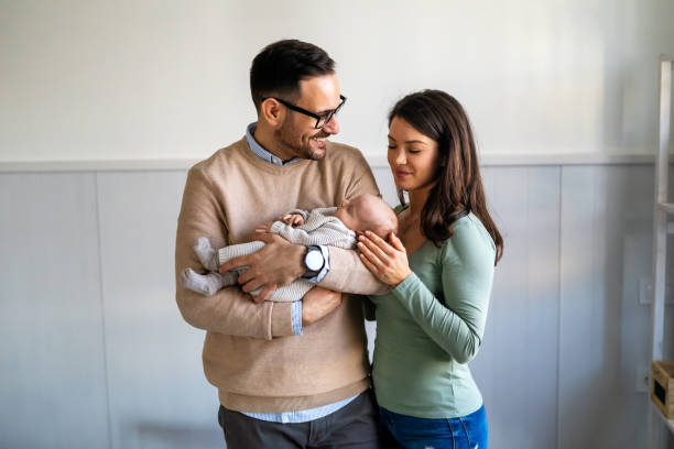 Proud mother and father smiling at their newborn baby daughter, son at home Proud mother and father smiling at their newborn baby daughter, son at home. Happy family concept biracial newborn stock pictures, royalty-free photos & images