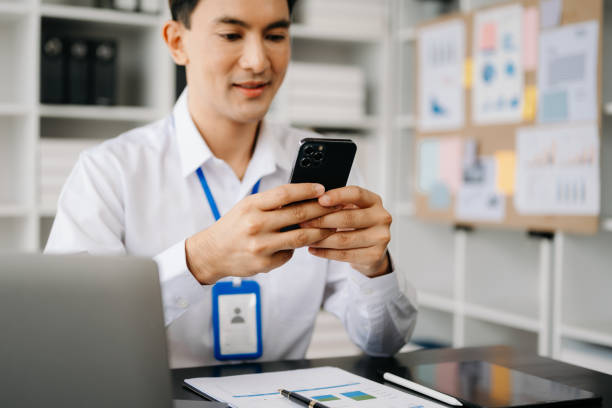 istock Business Asian man hand using smart phone laptop and tablet with social network diagram on desk as concept in morning light. 1496881521