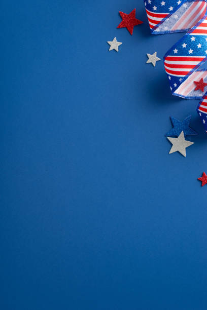 istock Vertical overhead perspective of Independence Day celebration items. Curly serpentine and glitter stars on a blue background with an empty space for text or advert 1496884596
