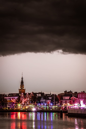 A stunning view of a bustling cityscape at night, illuminated by the shimmering lights along the waterfront in Alkmaar