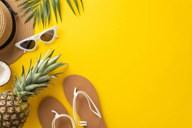 istock Immerse yourself in the summer relaxation with this top view flat lay. With a sunhat, palm leaves, flip-flops, coco nut and a pineapple on a bright yellow background, the empty space for text 1496885234