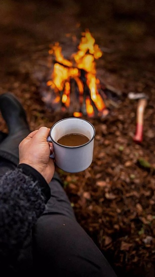 A cup of coffee when camping in front of campfire