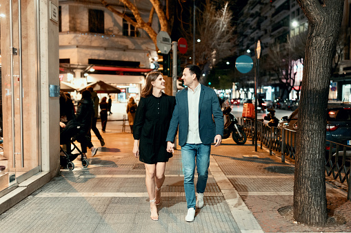 Beautiful couple walking down the street by night