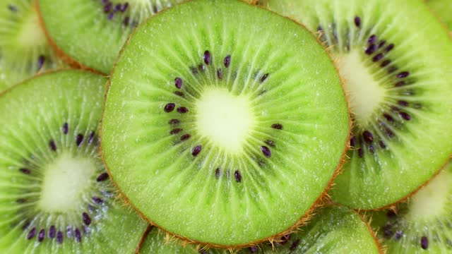 Bright green fresh kiwi slices rotation close up top view
