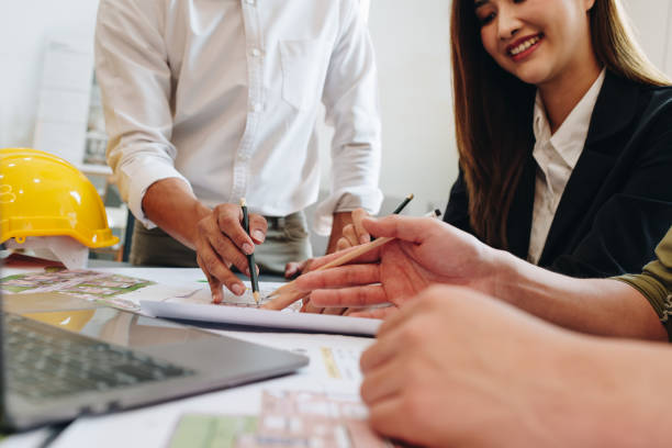 istock multi ethnic engineer brainstorming and measuring for cost estimating on paperworks and floor plan drawings about design architectural and engineering for houses and buildings 1496888172
