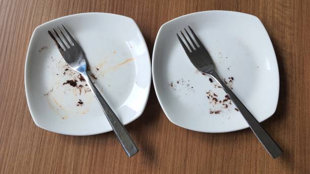 istock Two dirty plate with food leftovers and fork on table, high angle view 1496888564
