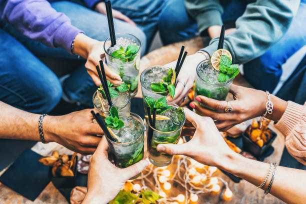 Multiracial group of young people cheering Mojito cocktails at bar pub enjoying summer party - Happy friends drinking fancy drinks sitting restaurant table- Food and beverage concept-Youth culture Multiracial group of young people cheering Mojito cocktails at bar pub enjoying summer party - Happy friends drinking fancy drinks sitting restaurant table- Food and beverage concept-Youth culture cocktail bar busy stock pictures, royalty-free photos & images
