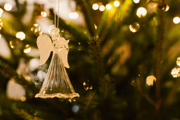 istock Clear glass angel ornament on a lush green Christmas tree branch 1496890321