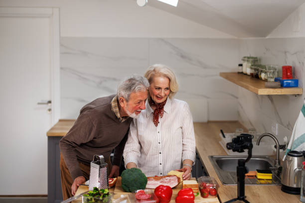 istock A senior couple is preparing dinner and filming it for the vlog. 1496891526