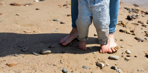 istock Children's bare feet on the sand by the sea. 1496893488