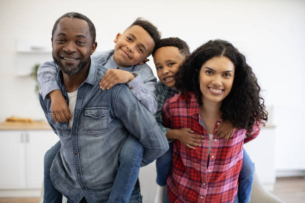 istock Adults with children on backs looking at camera at home 1496893637