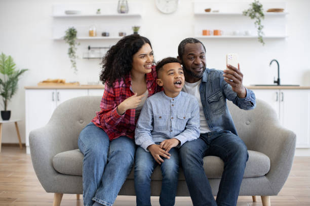 istock Spouses with son having online phone call in lounge at home 1496893697