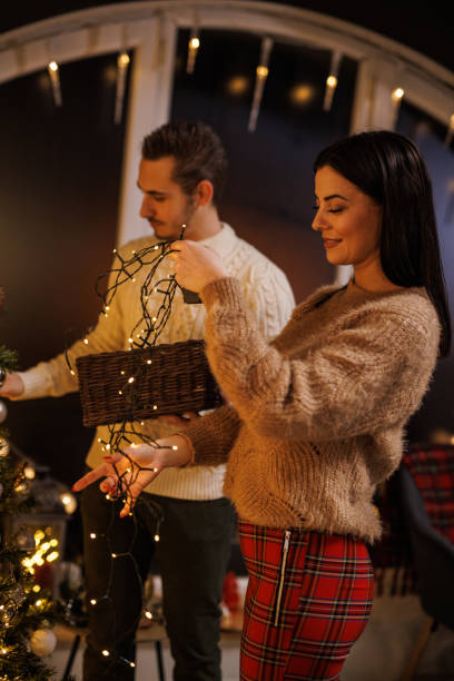 istock Young couple having romantic, bonding moments when decorating the Christmas tree together 1496894409