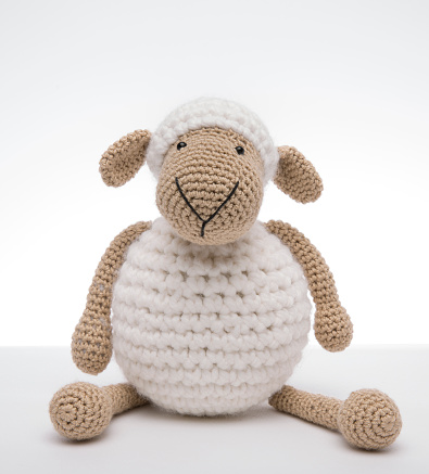 A crochet Amigurumi toy of a of cute stuffed white sheep.