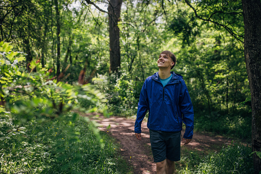Young man hiking in the forest and enjoying nature