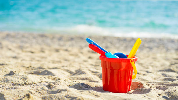 Red children's bucket with sand and toys on the seashore Red children's bucket with sand and toys on the seashore sandcastle structure stock pictures, royalty-free photos & images