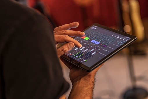 A skilled sound engineer uses a tablet to fine-tune the audio levels during a dynamic live concert performance.