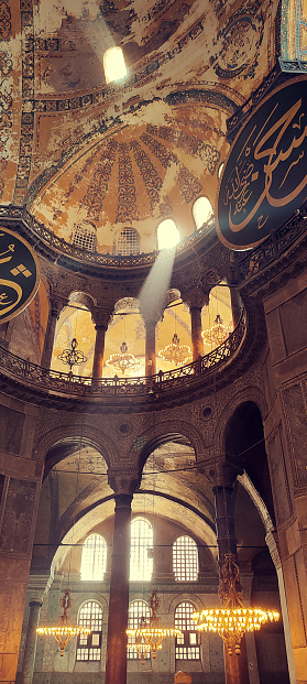 Interior of Istanbul's Santa Sophia Cathedral, with intricate decorations, arches, and divine rays of light streaming through the windows, creating a captivating ambiance in this vertical photo