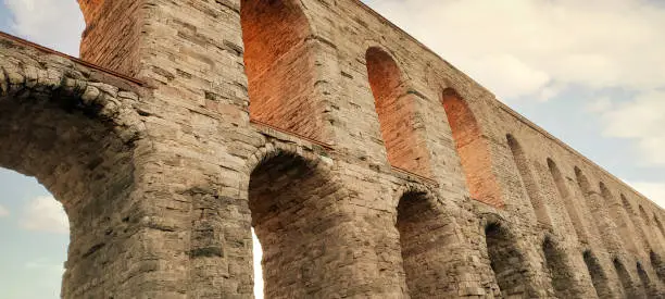 Photo of The majestic Valente or Bozdoğan Aqueduct in Istanbul, Turkey, stands tall, casting a captivating silhouette against the sky at sunset. Ancient architectural marvel for a touristic postcard