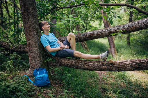 Young man reading a book in forest and enjoying nature