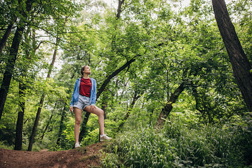 Young woman hiking in the forest and enjoying nature