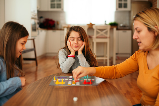 Mother and two children having fun playing board game at home