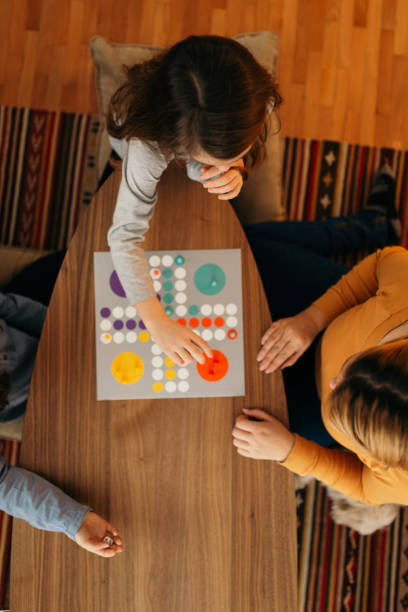 テーブルに座ってボードゲームをする家族 - leisure games dice indoors table ストックフォトと画像