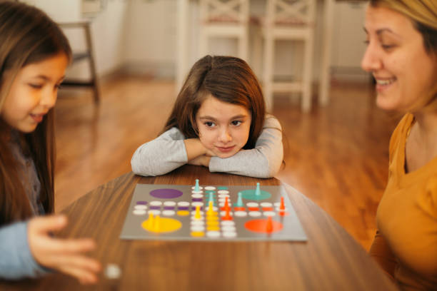 istock Mother and children having fun playing board game at the table at home 1496899346