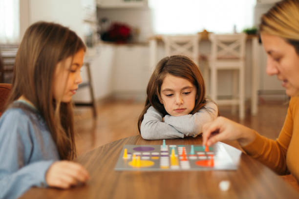 istock Mother and children having fun playing board game at the table at home 1496899388