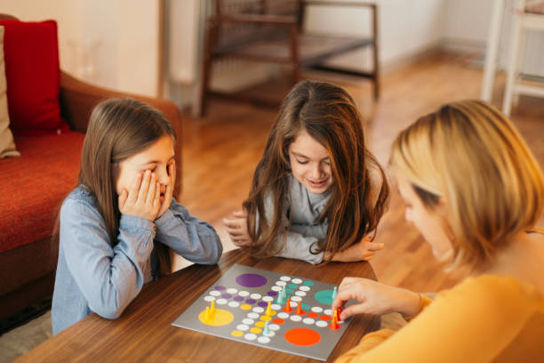 istock Mother and children having fun playing board game at the table at home 1496899414