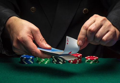A card sharper pulls an ace of diamonds from a deck of playing cards while playing poker. The concept of cheating in a poker club