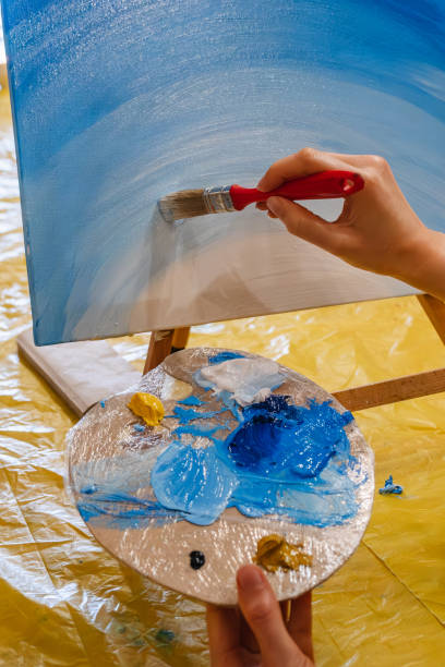 istock woman hand holding brush paint on canvas 1496904529