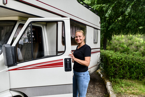 Portrait Of Cute Blond Female And Her RV Motorhome In Nature