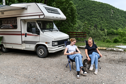 Mother And Daughter On Camping Trip With RV And Dog