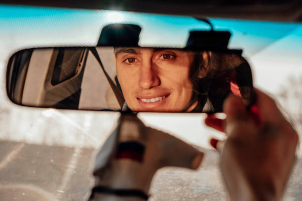A smiling man adjusts the rearview mirror of the car stock photo