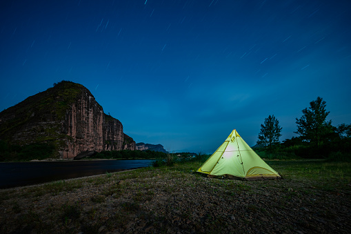 Tents for camping by the river at night, stars in the sky