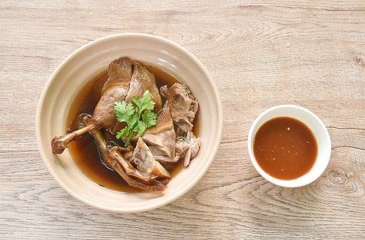 boiled duck meat in black soybean soup in bowl dipping spicy chili sauce