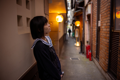 Woman standing on narrow street in Kyoto, Japan